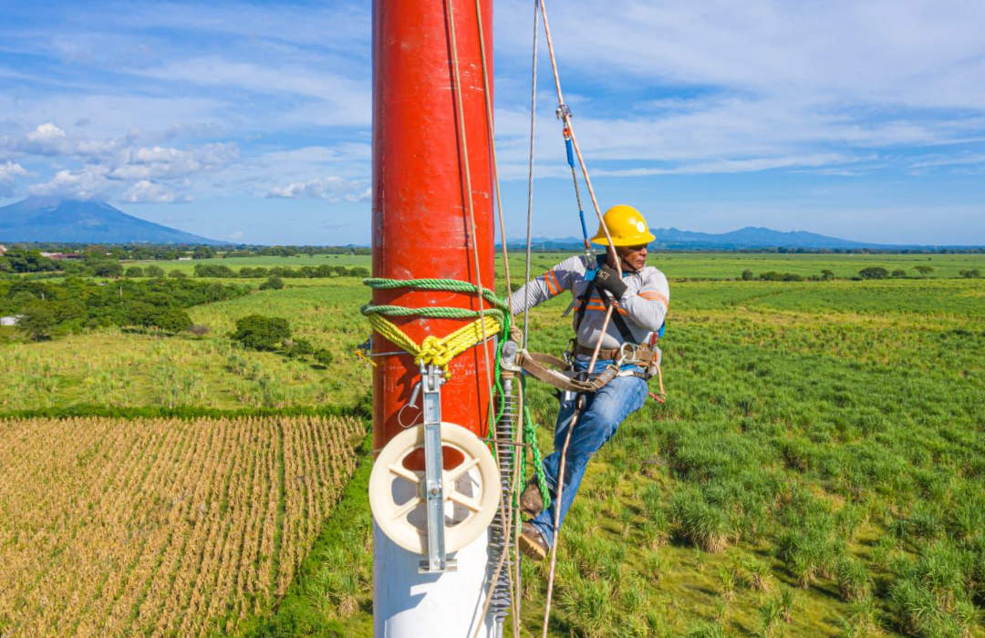 Technician working on a pole in a rural landscape